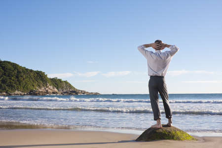 Businessman standing on a rock at the seaの写真素材
