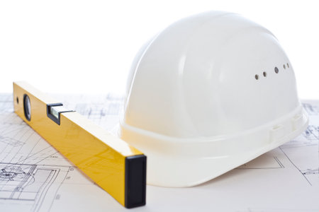 White hard hat and yellow level lying on construction plan - white background