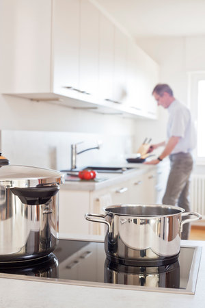 Mature man preparing a meal in a white kitchenの写真素材