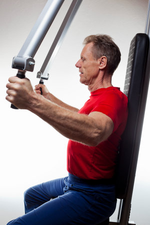 Mature strong man doing workout at a gym