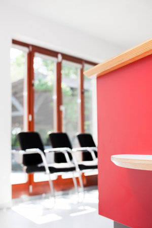 Bright waiting room in a hospital or office with red counter - focus on the counter in the foregroundの写真素材