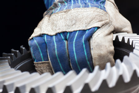 Hand of a mechanic carrying a big cog wheel - dark backgroundの写真素材