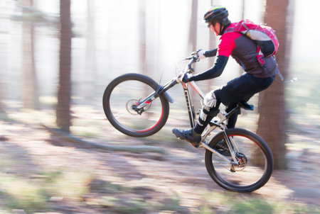 Man riding a mountain bike in a forest on a sunny day with fog - motion blurredの写真素材