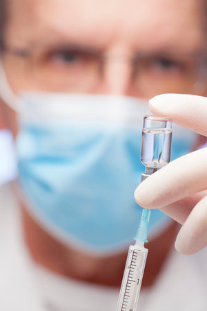 Close-up of doctor preparing a syringe for vaccination - focus on the syringeの写真素材