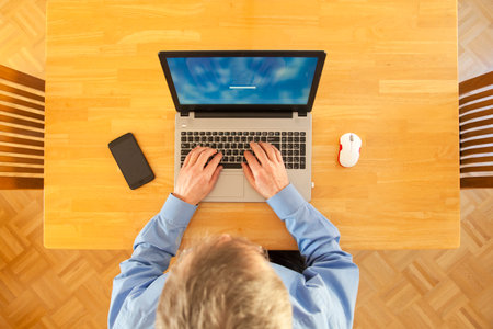 Businessman working remote with laptop from home trying to log in - focus on the keyboardの写真素材