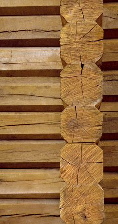 Rough russian chalet room of stacked aged beige hew cracky octagonal balks in traditional slavic style. Closeup view with space for text on crooked brown crack fond. Row of dried cut trunk bars decorの写真素材