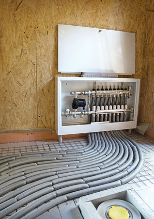 Modern manual laying of tuning hydronic gas firing conduit supply on metal mesh insulation indoor new building room. Ground repair texture. Detail close-up view with space for text on OSB backdropの写真素材