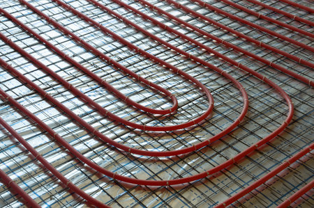 Modern manual laying of tuning water hydronic gas firing conduit supply on metal mesh insulation indoor new house room. Ground repair texture. Detail closeup macro view with space for text on grey netの写真素材