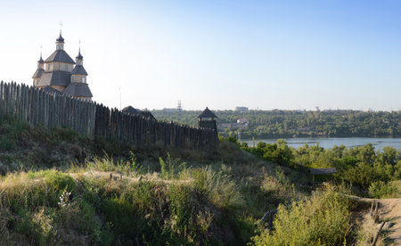 Fortified stockade settlement of Zaporizhzhya guard army troop 16-18 centuries. Panoramic view from Khortytsia island on broad Dnipro in quiet evening summertime sunset with space for text on blue skyの写真素材