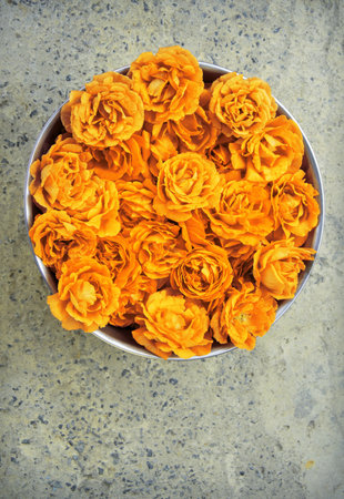 Bright romantic pure fresh light rosa flowerheads collected in steel bucket for drying for body spa salon skin care. Close up detail top view with copy space for text on grunge grey stone surfaceの写真素材
