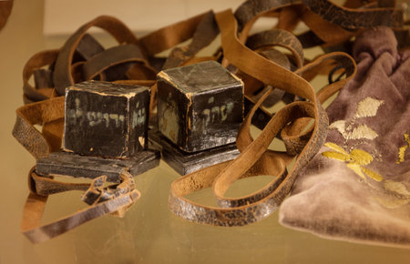 Teffilin or phylacteries. Two old small dark leather cubes with scrolls inscribed of verses from Torah, are worn by devout Jews during weekday morning God blessing. View closeup with space for textの写真素材