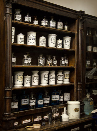 Museum Past of Physic Preparation. Kiev, Ukraine, 2017. Fluid in phial, powder in cap, poison in vial, ointment, herb elixir, flask set with text on label. Interior of obsolete brown wood storage caseの写真素材