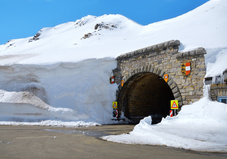 Beautiful great north austrian Alpen Hochtor mountainside terrain street pass in high crag. Big dark cavern in snowy scaur. Rural wintertime scenic view with space for text on bright blue skyの写真素材