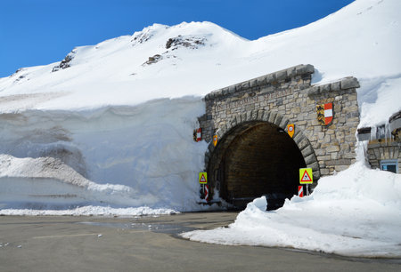 Beautiful great north austrian Alpen Hochtor mountainside terrain street pass in high crag. Big dark cavern in snowy scaur. Rural wintertime scenic view with space for text on bright blue skyの写真素材