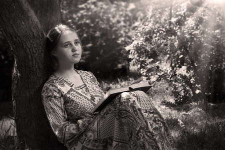 Pretty cute adult human sit rest relax look study old life hope. Sun light day backdrop open page closeup view text space. Antique kid lady holy Christ god gospel church school history hobby studentの写真素材