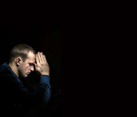 Dramatic orthodox evangelical baptist pious lonely stress mourn young white guy kneeling for ask implore wish upwards Jesus Christ. Modern think concept copyspace with space for text on dark backdropの写真素材