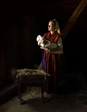 Happy young boy cradle sleep life symbol star light white cloth greet card text space. Dark black stable barn cave hay straw live scene cute new parent merry Lord messiah noel eve love joy lady handの写真素材