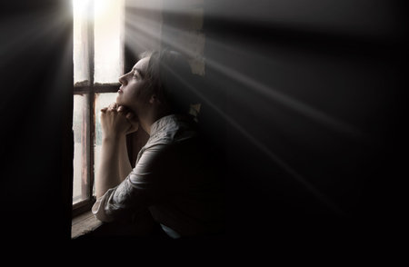Adult lone worry fail poor holy devot jew lady hand ask beg plead Jesus Christ old Ukraine war history. Cold young teen age human face think wait life love dark hut home room text space look light skyの写真素材