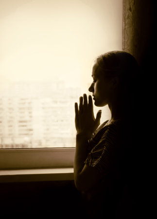 Pious orthodox lone pure worry pretty adult light white lady sit ask wish Lord Jesus Christ. Sin purity stress teen soul grace think life concept copyspace. Text space on dark black home room backdropの写真素材