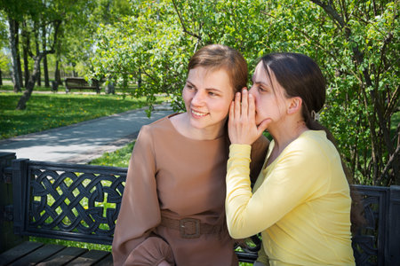 2 pretty young adult lady sit hear lie urban summer city town tree seat text space. Teen youth relation liar face eye see sunny happy cheer joy shock smile outside nature fun joke advice relax restの写真素材