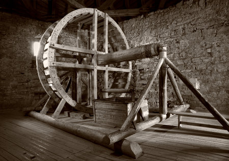 Close up view grunge European natur farming age large circle round handle rope gear hole turbine dark wheat grain flour barn wall. Big rusty iron metal river supply indoor farm home castle room culturの写真素材