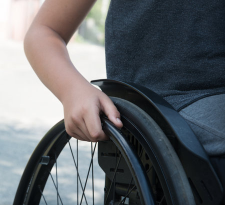 Closeup sad lone little teen male guy kid patient need aid help look town road nature text space. Close up active cerebral injured trauma young man seat upset suffer move stress play sport life hopeの写真素材