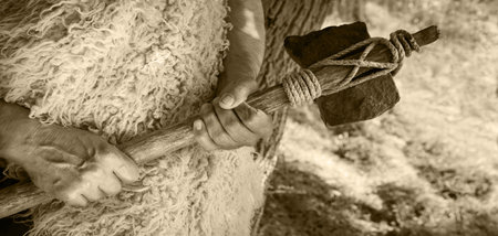 Closeup past retro primev archaic neolith era native culture craft mallet worker arm forest tree. Close up view dirty sharp steel iron stick rope beat nomad farm work signの写真素材