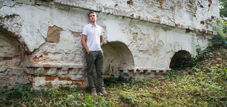 Young teen age mental fail despair frown grief upset guilty boy feel trust hope travel urban city town brick home ruin text space. Happy guy stand wait cry lost view retro church hillの写真素材