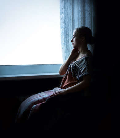 Pious orthodox lone pure worry pretty adult light white lady sit ask wish. Sin purity stress teen soul grace think life concept copyspace. Text space on dark black home room backdropの写真素材