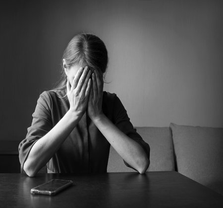 Young tired lost fail grief mood feel weep cry teen lady hand sit God faith hope dark home room wall text space. Adult ill sick guilty upset gloomy fear war widow think pain love shame device chat smsの写真素材