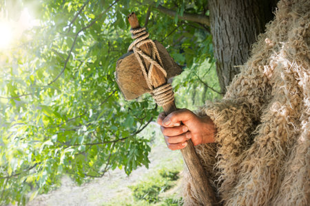 Closeup past retro primev archaic neolith era native culture craft mallet worker arm forest tree. Close up view dirty sharp steel iron stick rope nomad farm work signの写真素材
