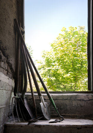 Retro ranch hand worker new begin care dig dirty green land soil dirt mud earth weed plant tree bush leaf foliage sky sun light life hobby. Closeup view dark hut door wood stick rusty iron metal handleの写真素材