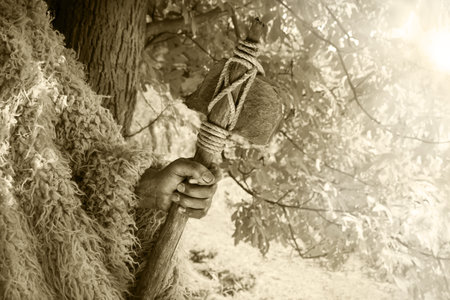 Closeup past retro primev archaic neolith era native culture craft mallet worker arm forest tree. Close up view dirty sharp steel iron stick rope nomad farm work signの写真素材