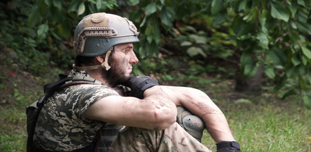 Alone tired USA patriot navy unit male guy sit rest hand protect look hope pain post danger dark forest tree bush text space. Lone worry human cry feel upset lost medic hero god faith worship conceptの写真素材