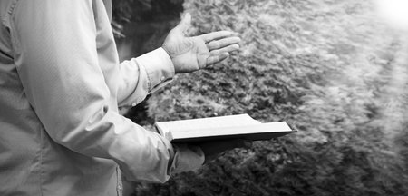 Sacred young saint devoted evangelic boy raise finger ask trust love hope open new word page park tree text space. Retro adult age guy arm historic urban city street garden conceptの写真素材