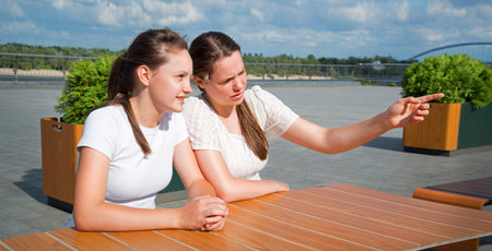 Young upset mood sad worry confus curious face emot lady sister sit bar table hand finger. Teen human meet hear angry envy conflict relation disput dialog look tell summer outdoor city river lake parkの写真素材