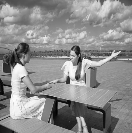 Young student upset mood worry stress trouble sad emot lady sister sit bar table break hand. Teen human meet hear envy gossip relation cry shout dialog crisis face look tell story city river lake parkの写真素材