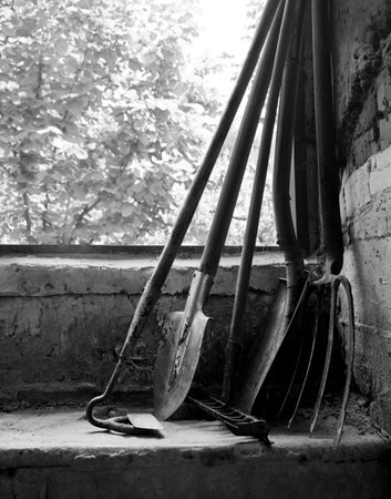 Retro ranch hand worker new begin care dig dirty green land soil dirt mud earth weed plant tree bush leaf foliage sky sun light life hobby. Closeup view dark hut door wood stick rusty iron metal handleの写真素材