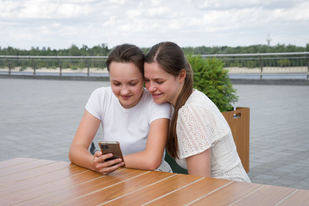 2 young age lady sister sit meet table feel excit surf hand type call app outside summer old city...