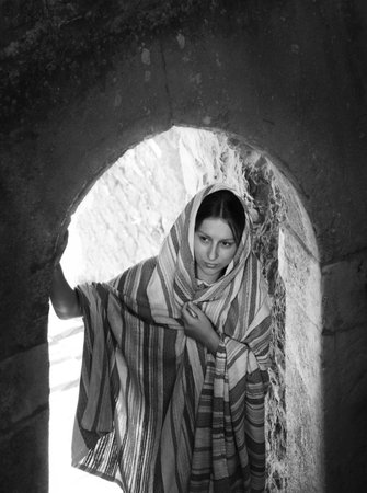 Lone sad worry human face think pray go alone come holy rise Lord god faith hope love light. Young man stand wait empty black rock fort wall light past age text spaceの写真素材