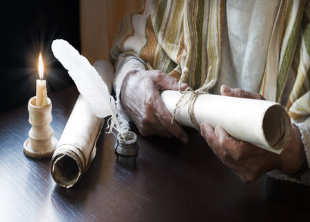 Close up view past age holy biblic god Jesus Christ faith belief law teacher Paul mail page sheet text space. Closeup arm inkwell quill art author diary jew female ink note learn dark black wood tableの写真素材