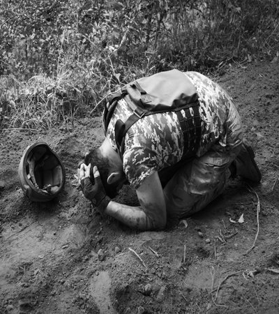 Alone tired USA patriot navy unit male guy sit kneel hand protect look hope pain post danger dark forest tree bush text space. Lone worry human cry feel upset lost medic hero god faith worship conceptの写真素材