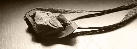 Close up detail macro view past age rough danger rubber hurt sport bullet aim lie blank tabl text space. Strong Israel hunter male jew human person fun kid boy hand pull gun hobby biblic story conceptの写真素材