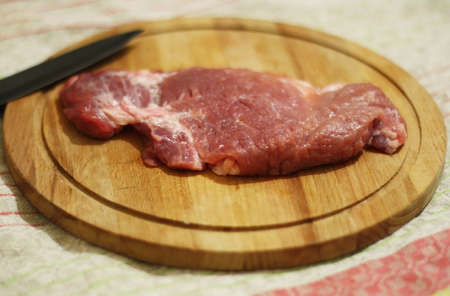 Fresh meat on a wooden round board.の写真素材