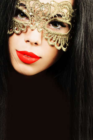 Glamour brunette woman in golden carnival maskの写真素材