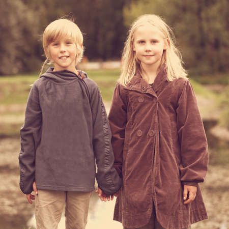Happy kids outdoors, little boy and girl holding hands
