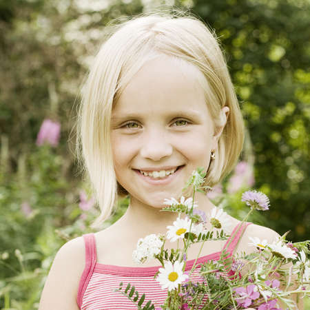 Portrait of smiling little girl with flowers outdoorsの写真素材