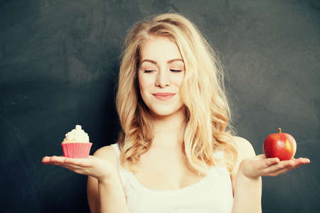 Woman with Healthy and Unhealthy Food. Difficult choice. Overweight Conceptの写真素材
