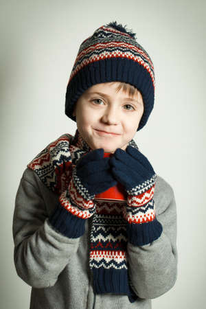 Happy child wearing a woolen hat and scarf drinking hot teaの写真素材