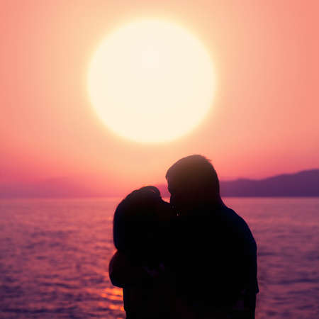 Young Couple Enjoying the Sunset on the Beach and Kiss. Silhouette of Man and Womanの写真素材